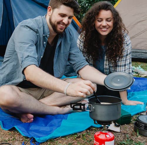 couple cooking before tents
